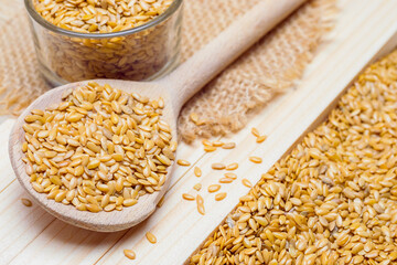 Golden flaxseeds or linseeds on wooden spoon, close up