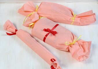 Presnts packed in pink paper with red and yellow ribbons on white background