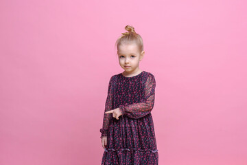 School Offer. girl in beautiful dress Pointing finger At  Space On pink Background In Studio