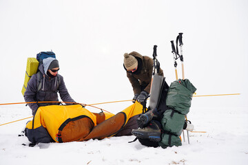 Two guys are setting up a tent in the snow. Setting up a tent during a winter expedition in extreme conditions. Winter trekking