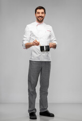 cooking, culinary and people concept - happy smiling male chef in jacket with pot or saucepan over grey background