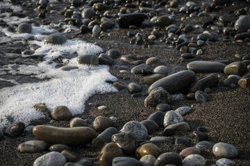 Sea shore with stones and foam, pebble seascape. 