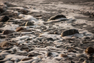 Sea shore with stones and foam, pebble seascape. 