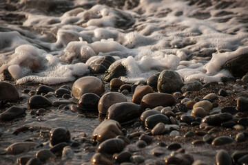 Sea shore with stones and foam, pebble seascape. 