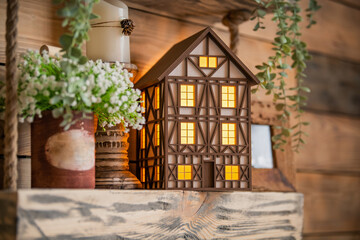 Fototapeta na wymiar toy decorative lamp house stands on wooden table among spring flowers and interior elements.