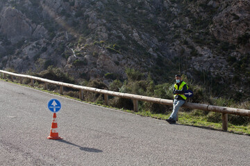 Road maintenance worker during the coronavirus pandemic, on a road with a stop sign and reflective vest