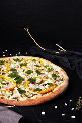 pizza on black textured background with dark napkin and golden sprigs