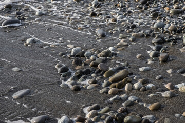 Sea shore with stones and foam, pebble seascape. 