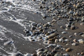Fototapeta na wymiar Sea shore with stones and foam, pebble seascape. 