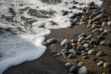 Sea shore with stones and foam, pebble seascape. 