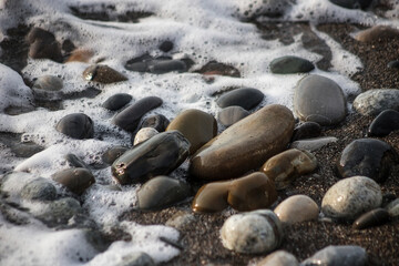Sea shore with stones and foam, pebble seascape. 