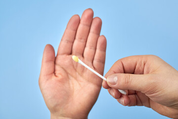 A woman's hand holds a cotton swab with earwax.
