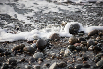 Sea shore with stones and foam, pebble seascape. 