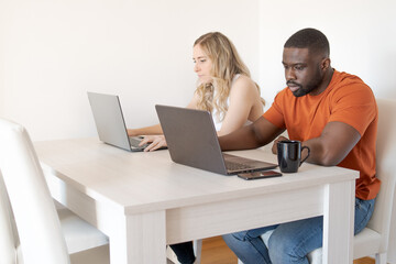side view of interracial couple working with laptops