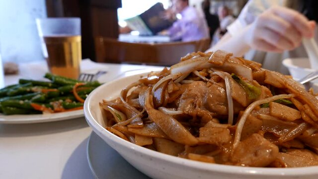 People eating congee with fried rice noodle on the table inside Hon's Chinese restaurant with 4k resolution.