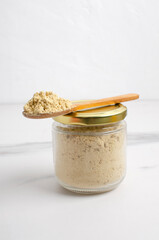 Vertical image.Glass jar full of mustard, wooden spoon and heap of mustard powder in it