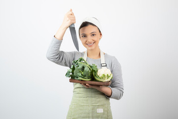 Picture of a smiling attractive woman holding a knife with a wooden plate