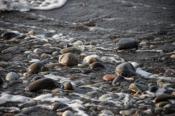 Sea shore with stones and foam, pebble seascape. 