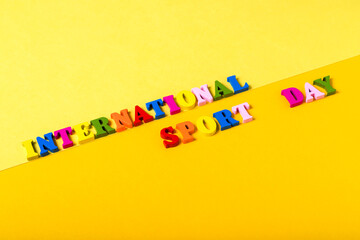 Wooden letters International Sports Day on a yellow background.