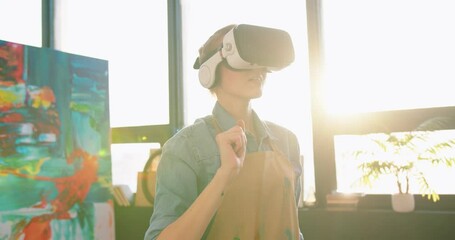 Close up of Caucasian happy woman painter in virtual reality glasses working in sunny art studio creating new project moving hands swiping hologram in air. Futuristic technology, contemporary artwork - Powered by Adobe