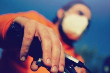 close up of a young man riding a bike wearing a surgical mask, concept of biking during Corona Virus