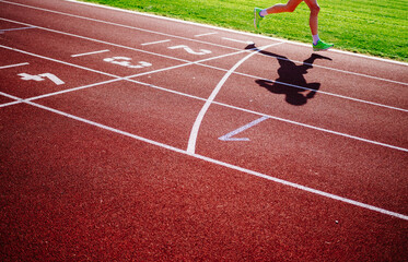 lower section of person running on tartan track