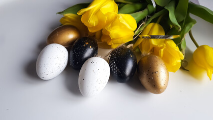 Easter composition of yellow tulips with and black and goid eggs. Copy space