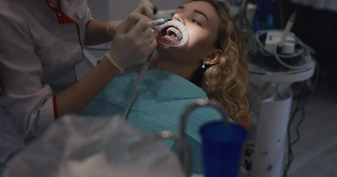 The orthodontist prepares a patient's teeth for installing braces