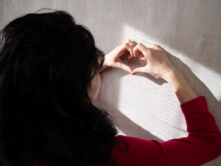 The girl holds her hands in the shape of a heart