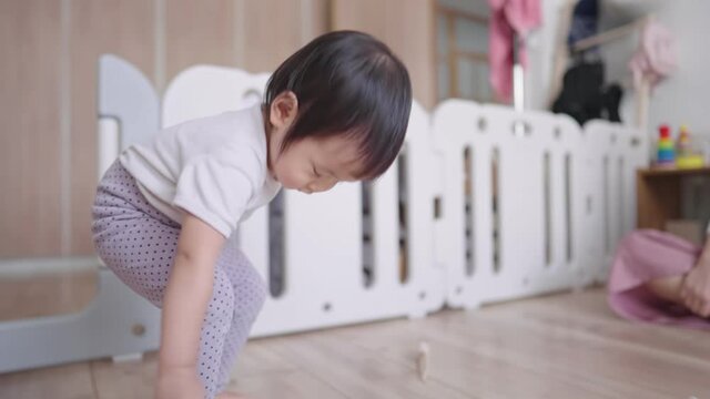 Cute toddler being watched out by her mother in playroom during a day, happy preschooler plays with a rope that tied with a toy car, imaginational activity in childhood at home, kid exercising