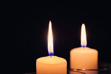 Two burning candles on the table in night dark. Flame of the hope and memory. Close up view with copy space.