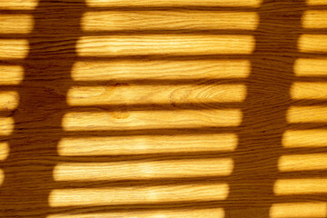 Blinds shadows on a light yellow wooden table. The texture of the lines. 