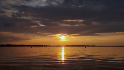 Beautiful golden sunset at the pond of lake Chiemsee with reflections in the water. Peaceful scene at the beach in summer