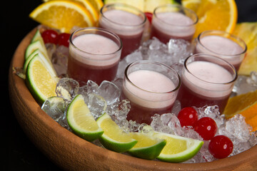 Red cocktail on ice and fruits