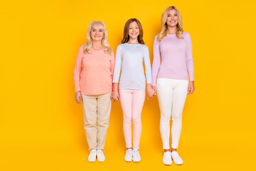 Full size photo of nice optimistic three woman grand mom daughter stand wear pastel cloth isolated on yellow color background