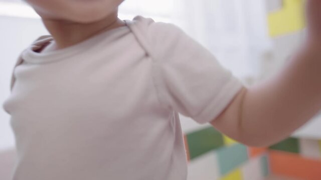 Portrait cute curious baby girl moves closely and toothy smiling in front of camera focus, an excited toddler feels so happy when seeing camera filming on her, assertive skill in childhood, future job