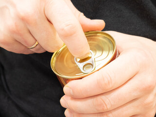 Male hands open a tin can of meat in close-up. Canned food for camp, travel, army, or others.