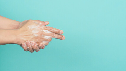 Fototapeta premium Hands washing gesture with foaming hand soap on green and Tiffany Blue background.