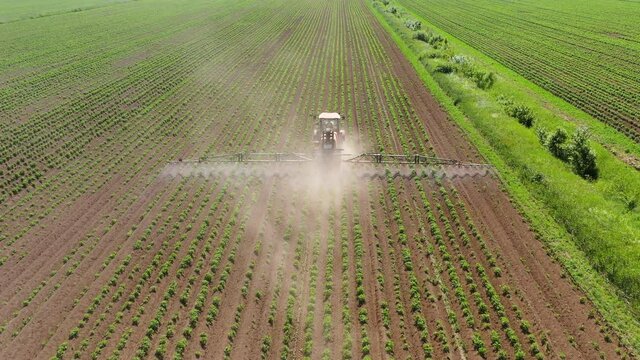 Tractor with pesticide fungicide insecticide sprayer on farm land, top view. Spraying with pesticides and herbicides crops.