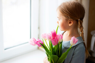  Little girl with pink tulips in her hands. Bouquet of flowers for mom on Mother's Day, valentine's day or birthday concept.