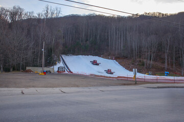 Snow machines make grade snow on a mountain side for snow sledding