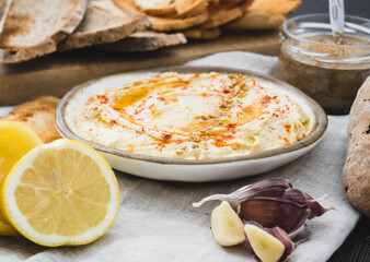 Healthy Homemade Creamy Hummus with the ingredients. Side view. A Mediterranean dish made of chickpea beans