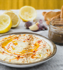 Healthy Homemade Creamy Hummus with the ingredients. Side view. A close-up Mediterranean dish made of chickpea beans