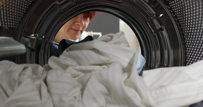 A broken washing machine. Women Housewife takes out laundry and a broken element the washing machine. Woman has problem with washing machine. View Looking Out From Inside Washing Machin