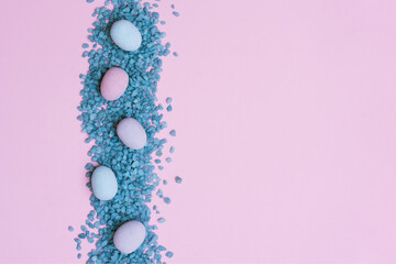 Easter eggs and blue stones on the pink background. Copyspace background.