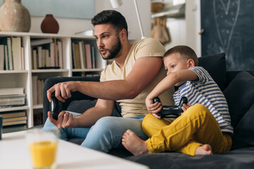 father and son playing video games in living room