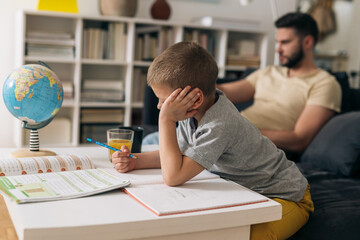 Naklejka premium father and son doing homework in living room