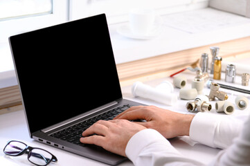 . Plumbing courses. On the table are a computer and accessories for the work of a plumber. Online learning