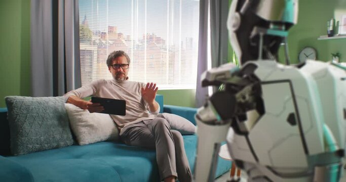 Mature man turning off android robot at home