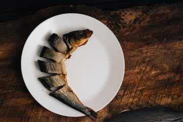 sliced dried fish on a white plate on a wooden table